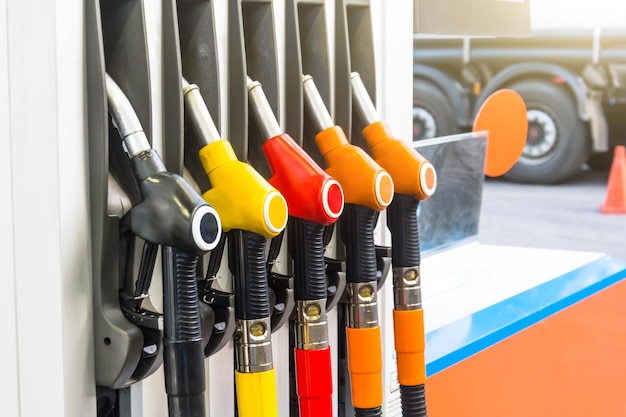 Pistolas de gasolina abastecendo carros na estação, contra o pano de fundo de uma roda de caminhão.