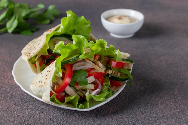 Pita gefüllt mit Hähnchenpfeffergurke und Kopfsalat auf weißer Platte Östliche Küche