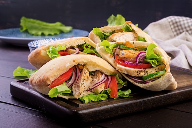 Pita rellena de pollo, tomate y lechuga en madera, cocina del Medio Oriente.