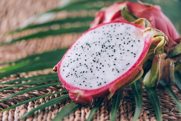 Pitahaya branca ou fruta do dragão com folhas de palmeira em fundo de rattan Copiar espaço Banner de design criativo Horário de verão Frutas exóticas de viagens tropicais Conceito vegano e vegetariano