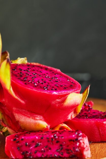 Pitahaya cortado em pedaços em um suporte de madeira em uma madeira preta