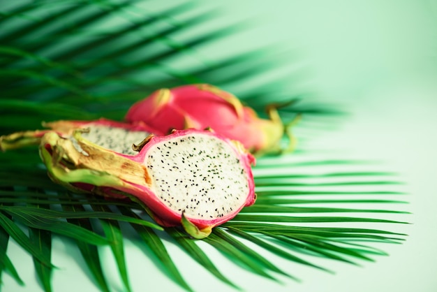 Pitahaya ou fruta do dragão sobre folhas de palmeira verdes tropicais no fundo de turquesa.