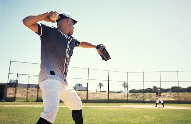 Foto pitch-sport und training mit einem mann auf dem baseballfeld für wettkampfleistungen und spiele. action-übungen und meisterschaften mit athleten, die im stadionpark für fitnesstraining und verein werfen