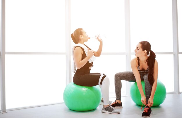 Piture de dos mujeres jóvenes sentados en green fitballs y descansar