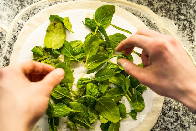 Pizaiolo bereitet Pizza im Restaurant mit frischen Zutaten zu Chef bei der Arbeit