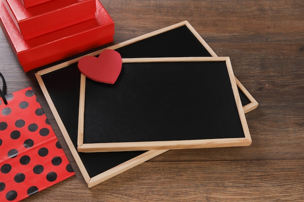 Pizarra con bolsa, regalo y corazones en la mesa de madera.