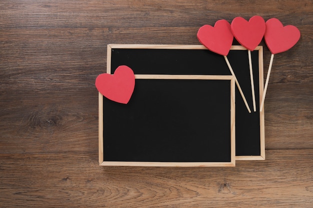 Pizarra con bolsa, regalo y corazones en la mesa de madera.