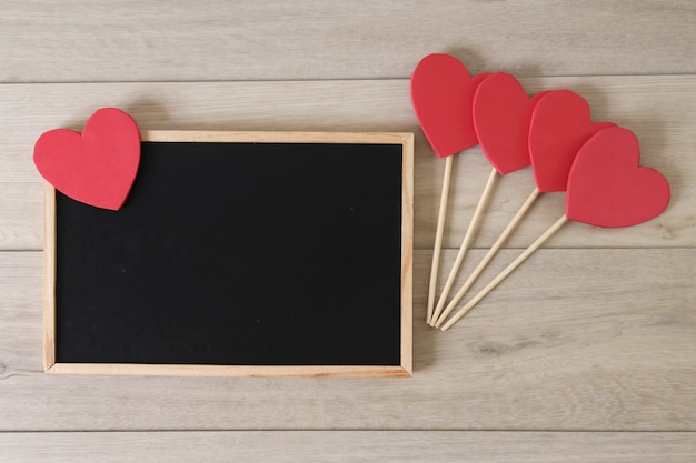 Pizarra y corazones sobre fondo de madera