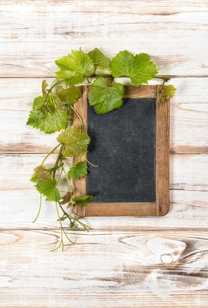 Pizarra con decoración de hojas de vid verde sobre fondo de madera brillante