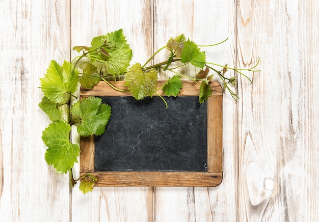 Pizarra con decoración de hojas de vid verde sobre fondo de madera brillante