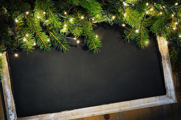 Foto pizarra decorada con ramitas de abeto y luces navideñas