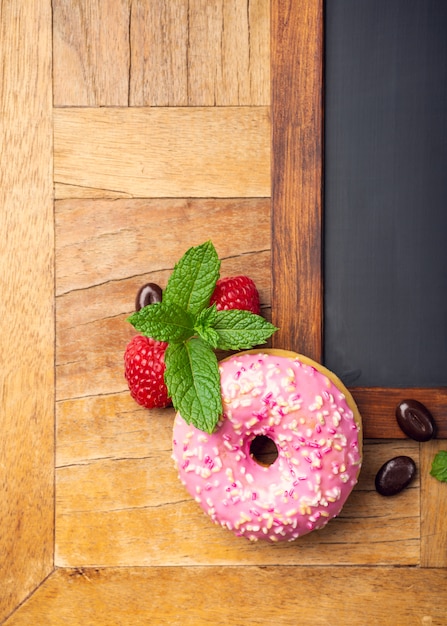 Foto pizarra negra con rosquilla esmaltada rosa