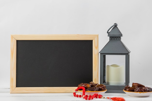 Pizarra rectangular pequeña con dátiles jugosos y candelero sobre fondo blanco