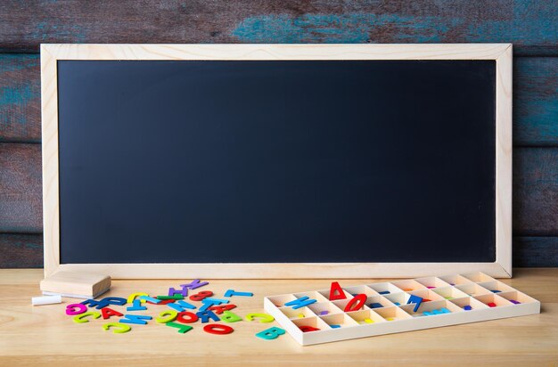 Pizarra de tiza magnética con letras del alfabeto de madera sobre la mesa Copiar espacio para diseño o agregar mensaje de texto Concepto de educación