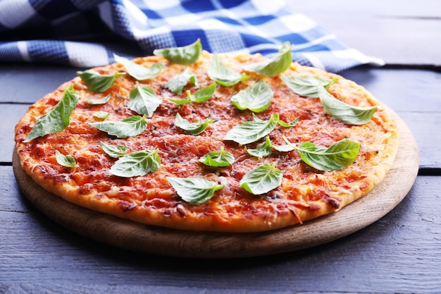 Pizza con albahaca en primer plano de mesa de madera