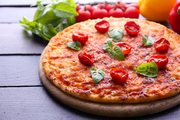 Pizza con albahaca y tomates cereza en un primer plano de mesa de madera