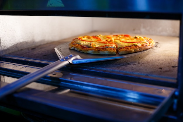 Pizza americana gostosa e saborosa com tomate, queijo e carne de crosta grossa em uma pá de metal