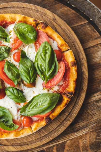 Pizza apetitosa con tomates y queso sobre un fondo de madera