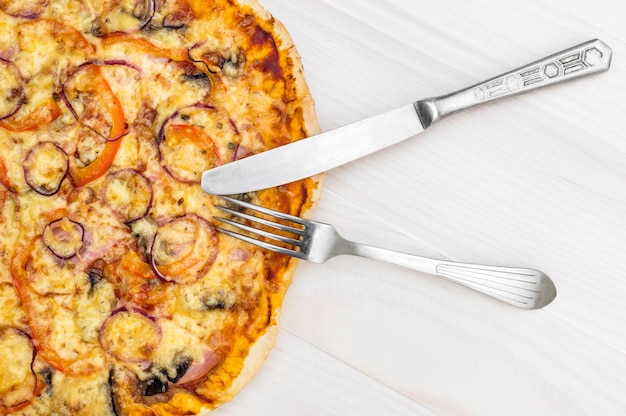 Pizza assada fresca com garfo e faca na mesa branca Vista superior