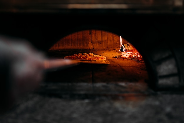 Pizza assando em forno de lenha.