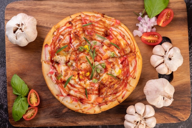 Pizza auf einem hölzernen Teller mit Pfeffersamen, Tomaten und Knoblauch