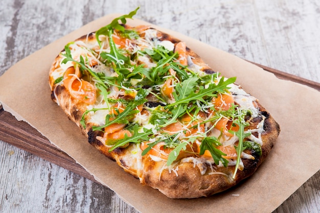 Pizza auf einem lockeren Teig mit leicht gesalzener Lachs-Käse-Pesto-Sauce und Rucola