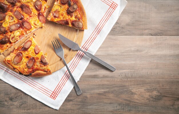 Pizza a bordo del círculo con un tenedor y un cuchillo.