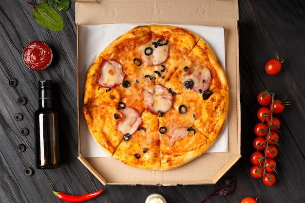 Pizza en una caja abierta con salsas de verduras frescas sobre un fondo de madera oscura
