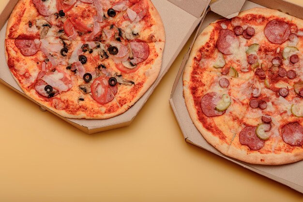 Pizza en caja de cartón corrugado marrón para llevar en mesa amarilla. redondo, pizza