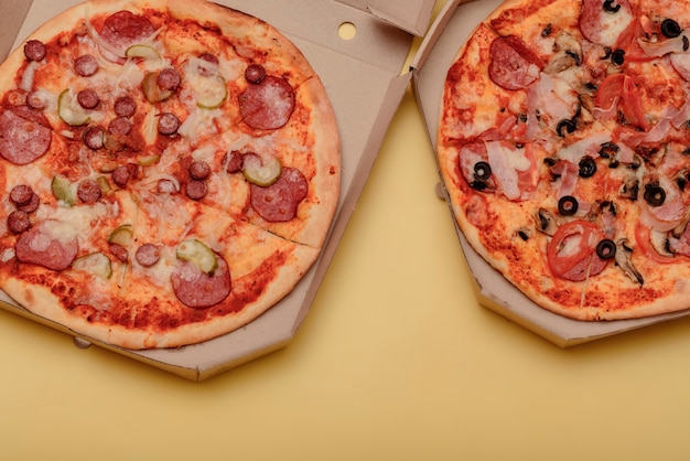 Pizza en caja de cartón corrugado marrón para llevar en mesa amarilla. redondo, pizza