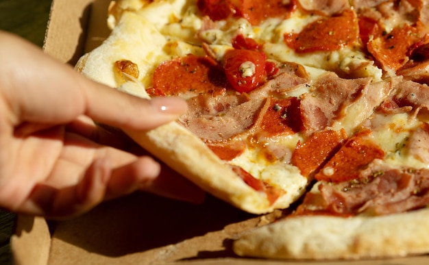 Foto pizza en una caja de cartón en una pizarra oscura vista superior del paquete de pizza entrega de pizza