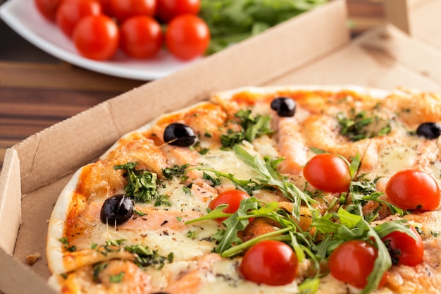 Pizza en caja de cartón sobre una mesa de cerca