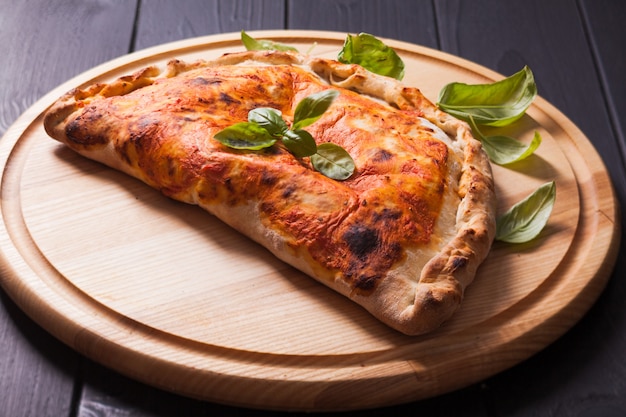 Pizza calzone com folhas de manjericão de perto