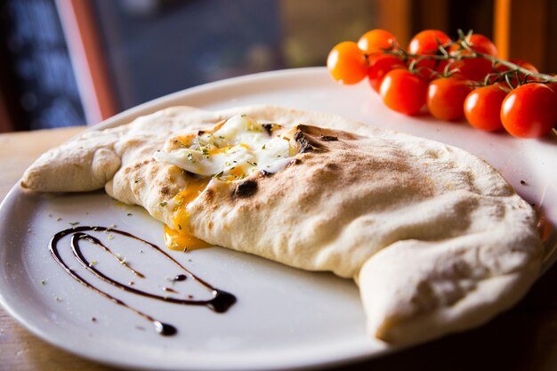 Foto pizza calzone. pizza napolitana rellena de queso, tomate y otros ingredientes como carne.