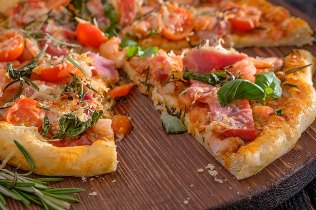 Pizza con camarones, queso, albahaca y tomates sobre una superficie de madera