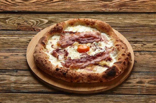 Pizza carbonara com bacon e ovo em fundo de madeira