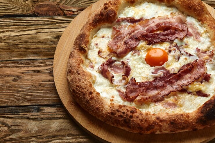 Foto pizza carbonara com bacon e ovo em fundo de madeira