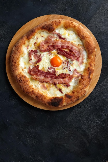 Pizza carbonara com bacon e ovo em fundo escuro de pedra