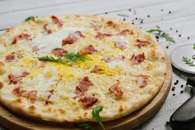 Pizza Carbonare mit Mozzarella, Becon, Ei und Zwiebel auf dem weißen Hintergrund