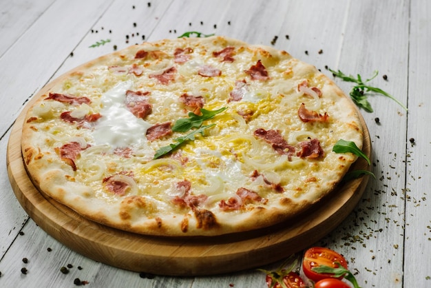 Pizza Carbonare mit Mozzarella, Becon, Ei und Zwiebel auf dem weißen Hintergrund