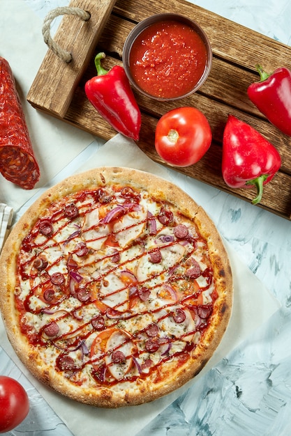 Pizza de carne al horno casera con tomate, queso, salchichas, salsa roja. Composición con pizza crujiente, tomates .. Vista superior