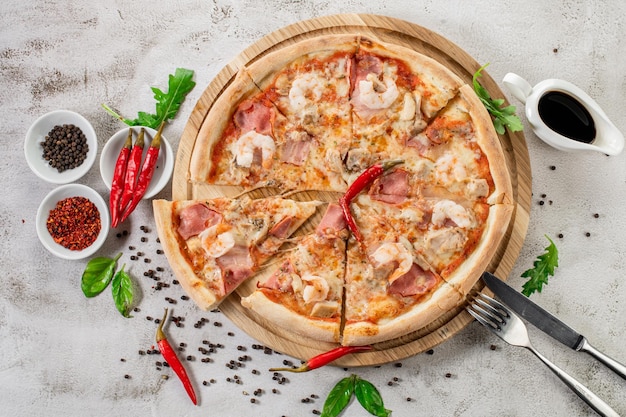 Pizza de carne con jamón y queso en el fondo de hormigón blanco