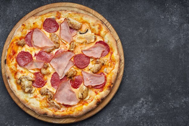 Pizza con carne, salchichas, carne y champiñones sobre un fondo gris con lugar para el texto. Pizza 4 carne