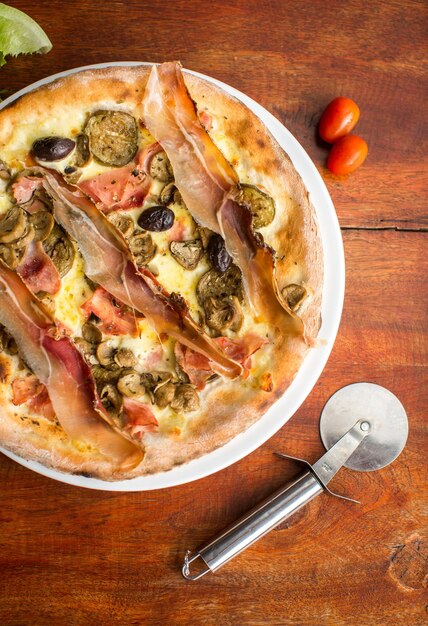 Pizza de carne variada con jamón y aceitunas