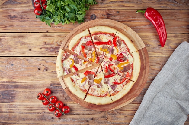 Pizza con carne, verduras y setas, fondo de madera