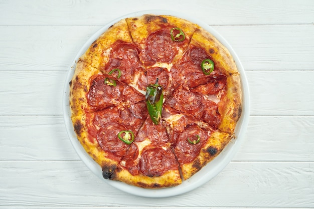 Pizza caseira apetitosa com salame de chouriço, pimenta e queijo derretido em um branco