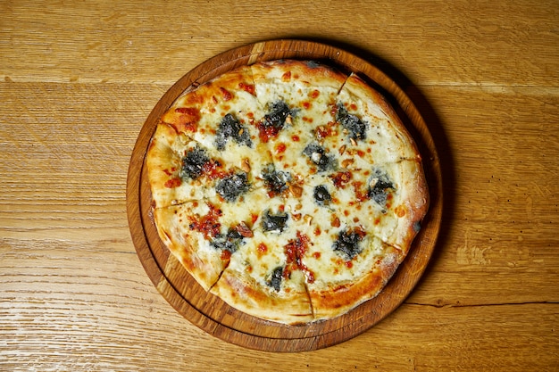 Pizza caseira clássica de quatro queijos com mussarela e gorganzola. Cozinha italiana. Comida de vista superior. Mesa de madeira.