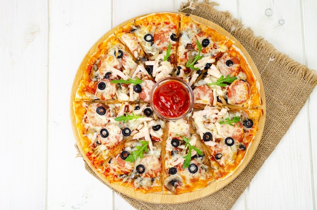 Pizza caseira com salame, presunto e mussarela na mesa de madeira. Foto de estúdio