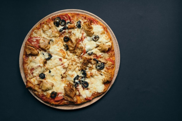 Pizza caseira com tomate, mussarela e manjericão. Vista superior com espaço de cópia na mesa de pedra escura