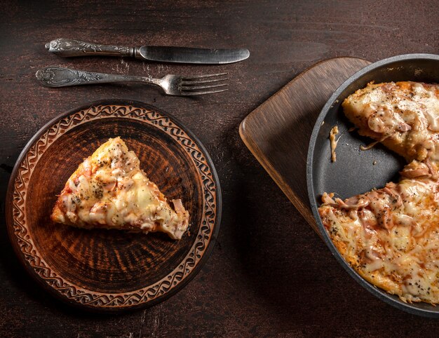 Pizza caseira com tomate, mussarela e presunto em uma mesa de madeira